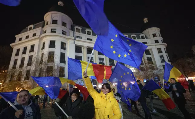 People wave Romanian and European Union flags during a pro-European rally ahead of the country's Dec. 8 runoff presidential elections in Bucharest, Romania, Thursday, Dec. 5, 2024. (AP Photo/Andreea Alexandru)