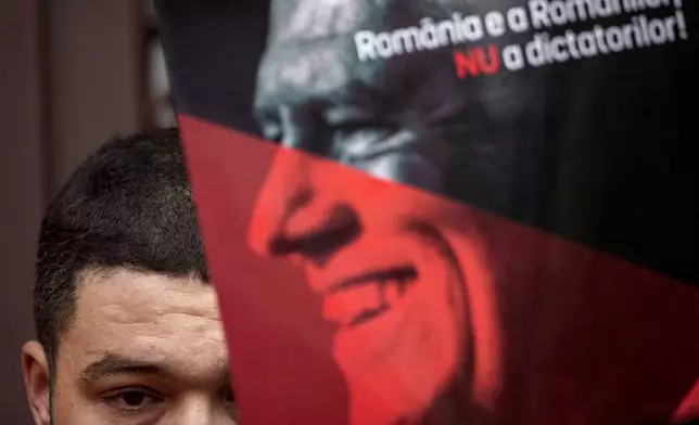 Supporters of the right wing Alliance for Unity of the Romanians (AUR) hold posters of Romania's President Klaus Iohannis reading "Iohannis Enough - Romania belongs to Romanians, not to dictators" in Bucharest, Romania, Sunday, Dec. 8, 2024. (AP Photo/Andreea Alexandru)