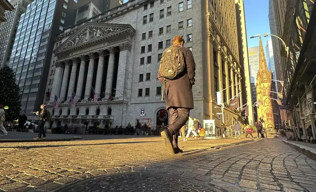 A person walks on Wall St. near the New York Stock Exchange in New York's Financial District on Wednesday, Dec. 4, 2024. (AP Photo/Peter Morgan)