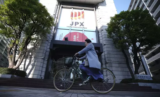 A person rides a bicycle in front of Tokyo Stock Exchange building Tuesday, Dec. 3, 2024, in Tokyo. (AP Photo/Eugene Hoshiko)