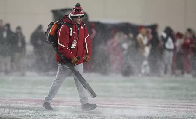 FILE - A worker cleans snow from the field during the first half of an NCAA college football game between Indiana and Purdue, Nov. 30, 2024, in Bloomington, Ind. (AP Photo/Darron Cummings, File)