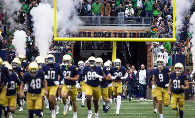 FILE - Notre Dame players run out from under the "Here Come The Irish" sign before the first half of an NCAA college football game against Virginia, Saturday, Nov. 16, 2024, in South Bend, Ind. (AP Photo/Michael Caterina, File)