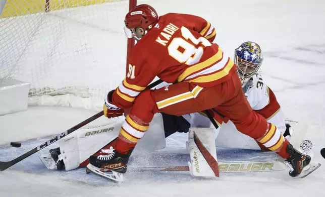 Florida Panthers goalie Spencer Knight, right, fails to stop Calgary Flames' Nazem Kadri, left, from scoring during first-period NHL hockey game action in Calgary, Alberta, Saturday, Dec. 14, 2024. (Jeff McIntosh/The Canadian Press via AP)