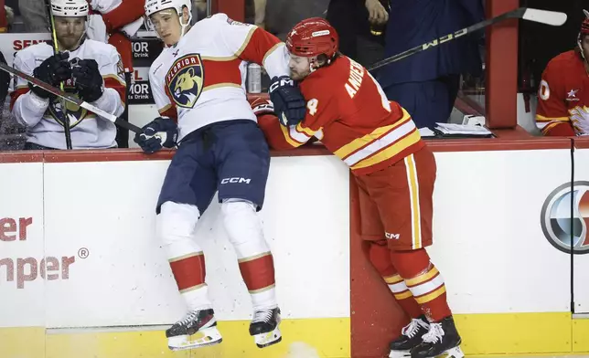 Florida Panthers' Gustav Forsling, left, checks Calgary Flames' Rasmus Andersson, right, during first-period NHL hockey game action in Calgary, Alberta, Saturday, Dec. 14, 2024. (Jeff McIntosh/The Canadian Press via AP)