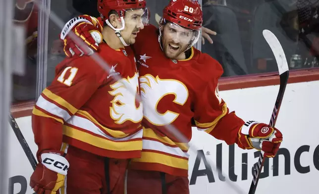 Calgary Flames' Mikael Backlund, left, celebrates his goal with teammate Blake Coleman during the third period of an NHL hockey game against the Florida Panthers in Calgary, Alberta, Saturday, Dec. 14, 2024. (Jeff McIntosh/The Canadian Press via AP)