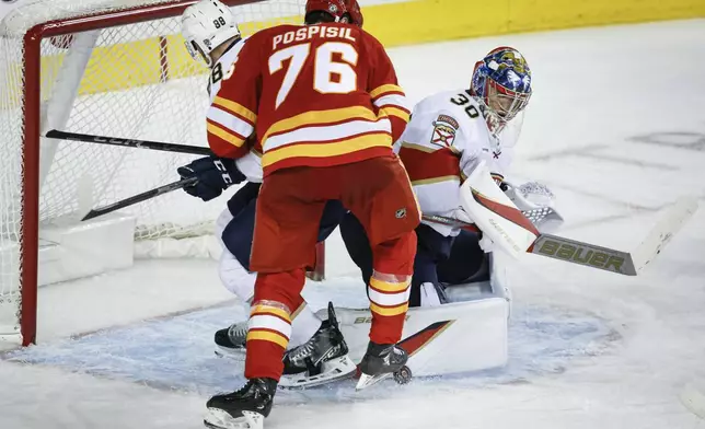 Florida Panthers goalie Spencer Knight, right, blocks the net as Calgary Flames' Martin Pospisil, center, is checked by Nate Schmidt during the third period of an NHL hockey game in Calgary, Alberta, Saturday, Dec. 14, 2024. (Jeff McIntosh/The Canadian Press via AP)