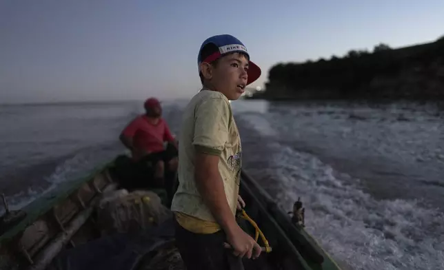 Milo Lautaro Sandoval gets his slingshot ready to hunt pigeons after assisting his neighbor Carlos Andino to fish in the Parana River in Villa Gobernador Galvez, Argentina, Wednesday, Dec. 11, 2024. (AP Photo/Rodrigo Abd)