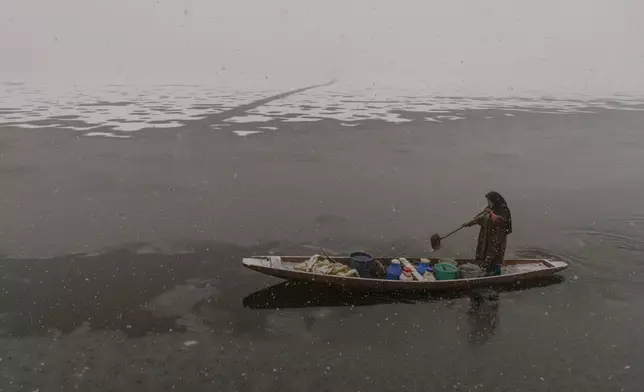 A Kashmiri rows her wooden boat filled with water canisters after collecting water from the Dal lake, as most taps and water reservoirs at residential houses have frozen due to an intense cold wave, in Srinagar, Indian Controlled Kashmir, Friday, Dec. 27, 2024. (AP Photo/Dar Yasin)