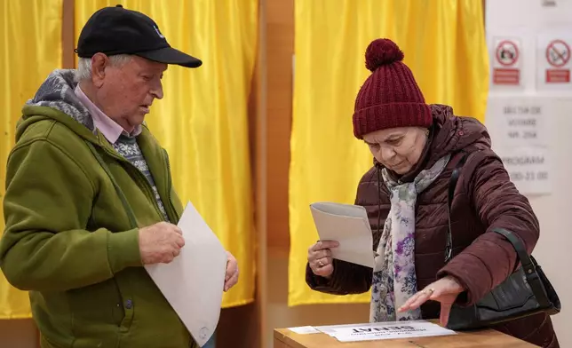 People prepare to cast their vote in the country's parliamentary elections, in Mogosoaia, Romania, Sunday, Dec. 1, 2024. (AP Photo/Andreea Alexandru)