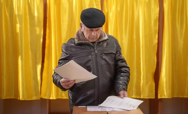 A man prepares to cast his vote in the country's parliamentary elections, in Mogosoaia, Romania, Sunday, Dec. 1, 2024. (AP Photo/Andreea Alexandru)