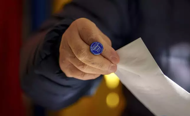 A man casts a vote for Romania's president a week before the country's Dec. 1 parliamentary elections, in Bucharest, Romania, Sunday, Nov. 24, 2024. (AP Photo/Andreea Alexandru)