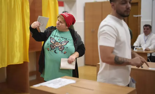 A woman holds ballot papers before casting her vote in the country's parliamentary election in Mogosoaia, Romania, Sunday, Dec. 1, 2024. (AP Photo/Vadim Ghirda)