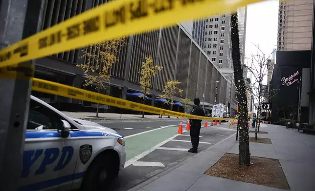 A New York police officer stands on 54th Street outside the Hilton Hotel in midtown Manhattan where Brian Thompson, the CEO of UnitedHealthcare, was fatally shot Wednesday, Dec. 4, 2024, in New York. (AP Photo/Stefan Jeremiah)