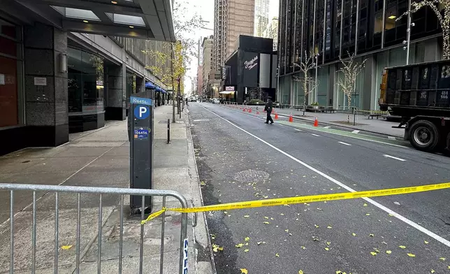 A New York police officer walks outside a hotel where a shooting occurred in midtown Manhattan, Wednesday, Dec. 4, 2024, in New York. (AP Photo/Joe Frederick)