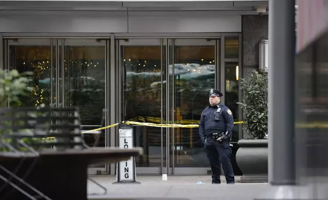 A New York police officer stands outside the Hilton Hotel in midtown Manhattan where Brian Thompson, the CEO of UnitedHealthcare, was fatally shot Wednesday, Wednesday, Dec. 4, 2024, in New York. (AP Photo/Stefan Jeremiah)