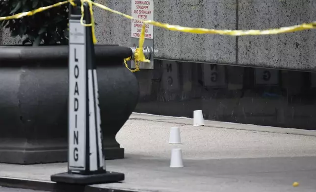 Paper cups mark spots at the scene outside the Hilton Hotel in midtown Manhattan where Brian Thompson, the CEO of UnitedHealthcare, was fatally shot Wednesday, Wednesday, Dec. 4, 2024, in New York. (AP Photo/Stefan Jeremiah)