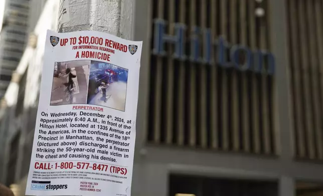 A reward poster hangs on a light pole outside the Hilton Hotel in midtown Manhattan where Brian Thompson, the CEO of UnitedHealthcare, was fatally shot ,Wednesday, Dec. 4, 2024, in New York. (AP Photo/Stefan Jeremiah)