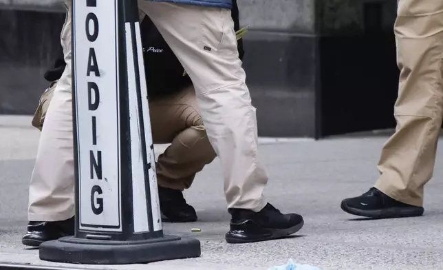 Members of the New York police crime scene unit investigate bullets lying on the sidewalk at the scene outside the Hilton Hotel in midtown Manhattan where Brian Thompson, the CEO of UnitedHealthcare, was fatally shot, Wednesday, Dec. 4, 2024, in New York. (AP Photo/Stefan Jeremiah)