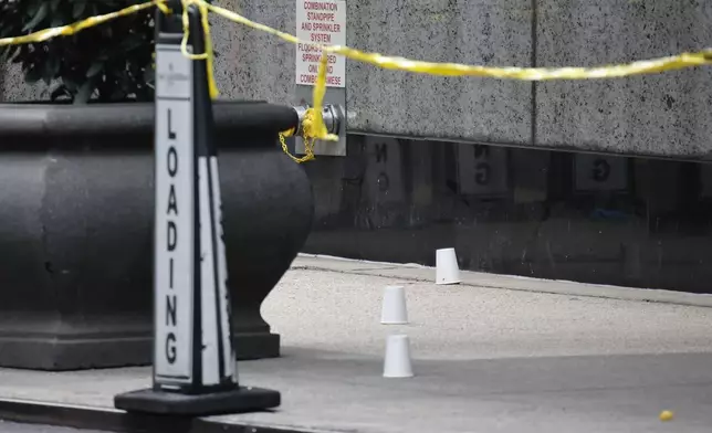 Paper cups mark spots at the scene outside the Hilton Hotel in midtown Manhattan where Brian Thompson, the CEO of UnitedHealthcare, was fatally shot, Wednesday, Dec. 4, 2024, in New York. (AP Photo/Stefan Jeremiah)