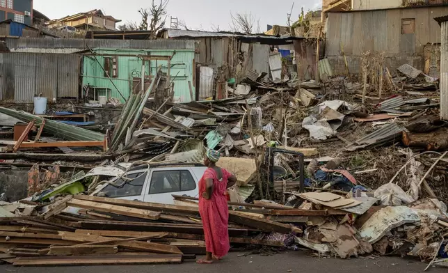 A woman looks at a destroyed home in Mamoudzou, Mayotte, Thursday, Dec. 19, 2024. (AP Photo/Adrienne Surprenant)