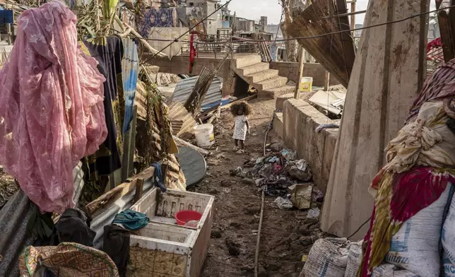 A young girl walks in the Kaweni slum on the outskirts of Mamoudzou, in the French Indian Ocean island of Mayotte, Thursday, Dec. 19, 2024, after Cyclone Chido. (AP Photo/Adrienne Surprenant)