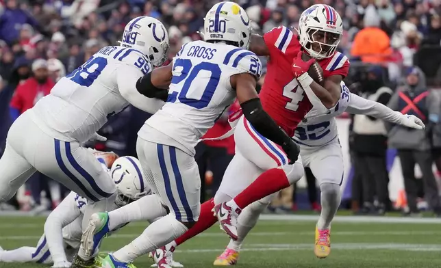 New England Patriots running back Antonio Gibson (4) carries for a touchdown against Indianapolis Colts defensive tackle DeForest Buckner (99) and safety Nick Cross (20) during the second half of an NFL football game, Sunday, Dec. 1, 2024, in Foxborough, Mass. (AP Photo/Steven Senne)