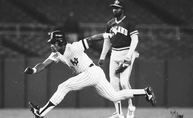 FILE - New York Yankees' Rickey Henderson, left, takes off to steal third base during a baseball game against the Oakland Athletics at Yankee Stadium in New York, May 21, 1986. (AP Photo/Ray Stubblebine, File)