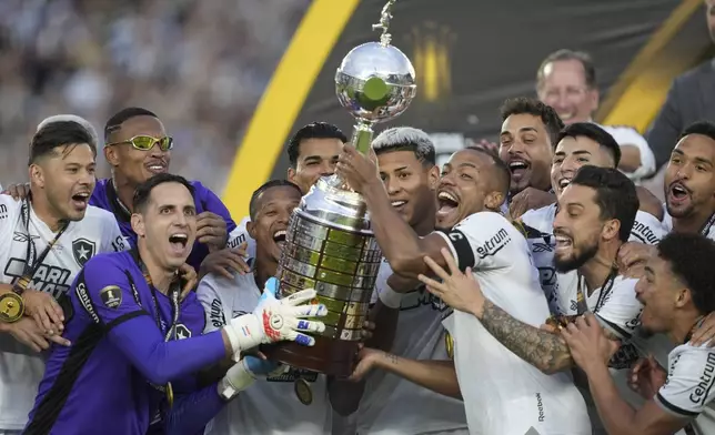 Players of Brazil's Botafogo hold the trophy as they celebrate after winning the Copa Libertadores final soccer match against Brazil's Atletico Mineiro at Monumental stadium in Buenos Aires, Argentina, Saturday, Nov. 30, 2024. (AP Photo/Gustavo Garello)