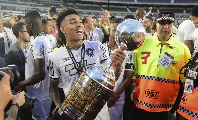 Igor Jesus of Brazil's Botafogo holds the trophy as he celebrates with teammates after winning the Copa Libertadores final soccer match against Brazil's Atletico Mineiro at Monumental stadium in Buenos Aires, Argentina, Saturday, Nov. 30, 2024.(AP Photo/Ignacio Amiconi)