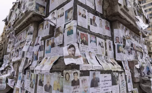 Portraits of missing people whose families say they were taken by the Assad regime are plastered across a monument in Damascus, Syria, Saturday, Dec. 28, 2024 (AP Photo/Mosa'ab Elshamy)