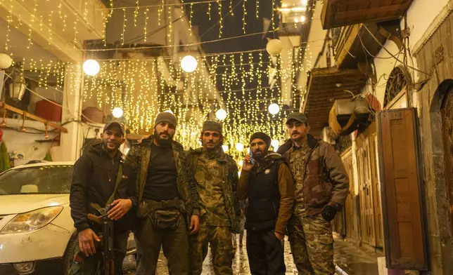 Members of the HTS rebel group that overthrew the Assad regime pose for a portrait in the ancient town of old Damascus, in Syria, Saturday, Dec. 28, 2024 (AP Photo/Mosa'ab Elshamy)