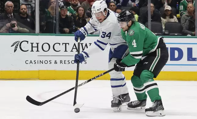 Toronto Maple Leafs center Auston Matthews (34) tries to get the puck by Dallas Stars defenseman Miro Heiskanen (4) during the second period of an NHL hockey game in Dallas, Wednesday, Dec. 18, 2024. (AP Photo/Michael Ainsworth)