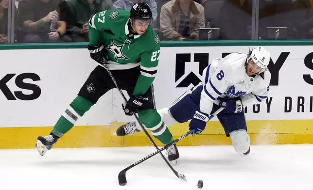 Dallas Stars left wing Mason Marchment (27) and Toronto Maple Leafs defenseman Chris Tanev (8) fight for the puck during the second period of an NHL hockey game in Dallas, Wednesday, Dec. 18, 2024. (AP Photo/Michael Ainsworth)