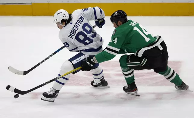 Dallas Stars left wing Jamie Benn (14) tries to get the puck from Toronto Maple Leafs left wing Nicholas Robertson (89) during the second period of an NHL hockey game in Dallas, Wednesday, Dec. 18, 2024. (AP Photo/Michael Ainsworth)