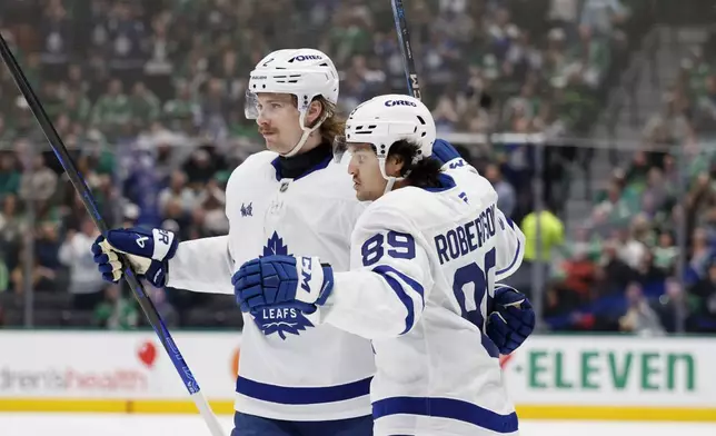 Toronto Maple Leafs left wing Nicholas Robertson (89) celebrates his goal against the Dallas Stars with defenseman Simon Benoit (2) during the second period of an NHL hockey game in Dallas, Wednesday, Dec. 18, 2024. (AP Photo/Michael Ainsworth)