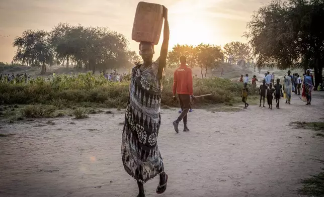 South Sudanese woman carries a jerrican of water in Jonglei state, South Sudan Thursday, Nov. 14, 2024. (AP Photo/Florence Miettaux)