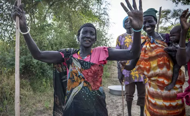 Bichiok Hoth Chuiny, 70, who has been displaced since 2021, gestures as she sings with her friends in Jonglei state, South Sudan, Thursday, Nov. 14, 2024. (AP Photo/Florence Miettaux)