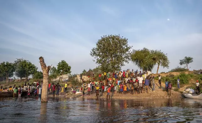 People gather along a flooded area in Jonglei state, South Sudan, Wednesday, Nov. 13, 2024. (AP Photo/Florence Miettaux)