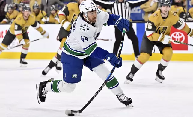 Vancouver Canucks left wing Kiefer Sherwood (44) takes a shot on goal against the Vegas Golden Knights during the first period of an NHL hockey game Thursday, Dec. 19, 2024, in Las Vegas. (AP Photo/David Becker)