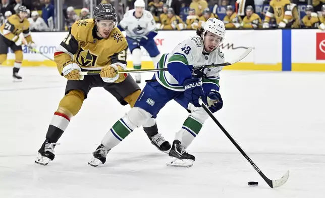 Vegas Golden Knights center Brett Howden (21) defends against Vancouver Canucks defenseman Quinn Hughes (43) during the second period of an NHL hockey game Thursday, Dec. 19, 2024, in Las Vegas. (AP Photo/David Becker)