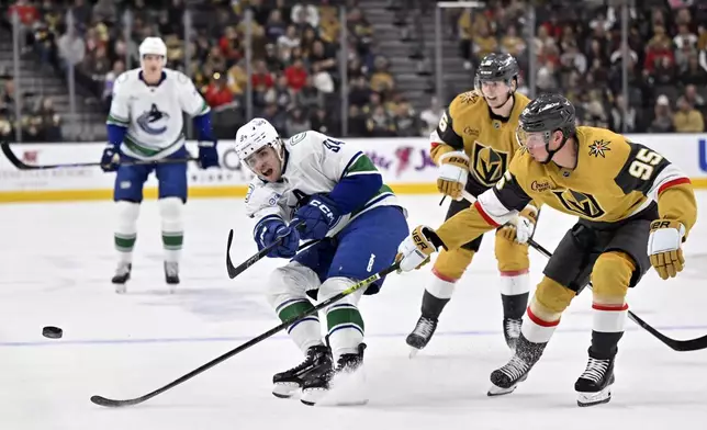 Vancouver Canucks center Linus Karlsson (94) hits the puck down ice against Vegas Golden Knights right wing Victor Olofsson (95) during the first period of an NHL hockey game Thursday, Dec. 19, 2024, in Las Vegas. (AP Photo/David Becker)