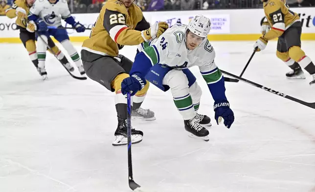 Vegas Golden Knights right wing Cole Schwindt (22) defends against Vancouver Canucks center Pius Suter (24) during the first period of an NHL hockey game Thursday, Dec. 19, 2024, in Las Vegas. (AP Photo/David Becker)