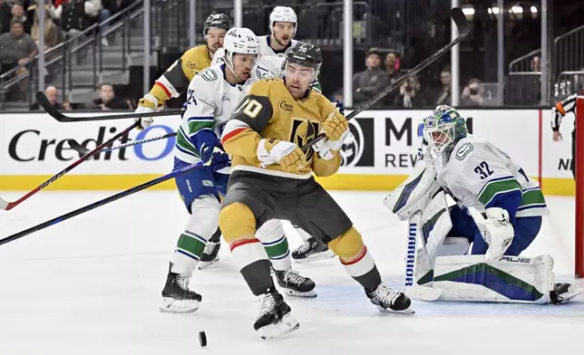 Vegas Golden Knights left wing Tanner Pearson (70) vies for the puck against Vancouver Canucks center Pius Suter (24) and goaltender Kevin Lankinen (32) during the second period of an NHL hockey game Thursday, Dec. 19, 2024, in Las Vegas. (AP Photo/David Becker)