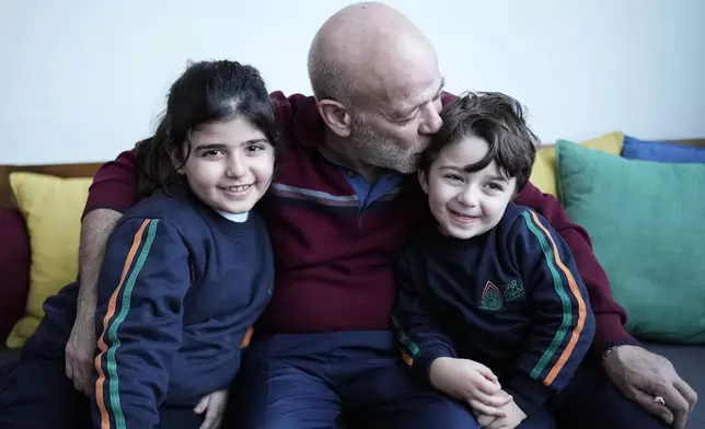 Suheil Hamwi, center, who spent 32 years in prison in Syria and returned to Lebanon after the government of Bashar Assad was toppled kisses his grandchildren at his home in Chekka, Lebanon, Tuesday, Dec. 10, 2024. (AP Photo/Hassan Ammar)
