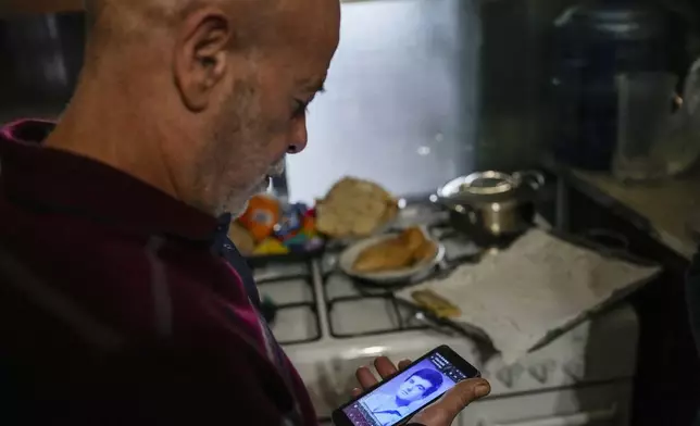Suheil Hamwi, who spent 32 years in prison in Syria, reacts as a man shows him a picture of a missing Lebanese prisoner inside Syria, at Hamwi's home in Chekka, Lebanon, Tuesday, Dec. 10, 2024. (AP Photo/Hassan Ammar)