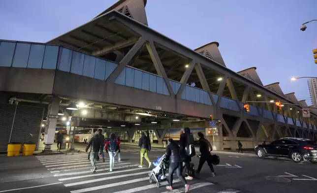 Pedestrians cross the road outside George Washington Bridge Bus Station in New York, Friday, Dec. 6, 2024, where the gunman fleeing Wednesday's shooting of UnitedHealthcare CEO Brian Thompson took a taxi to, according to surveillance video. (AP Photo/Richard Drew)