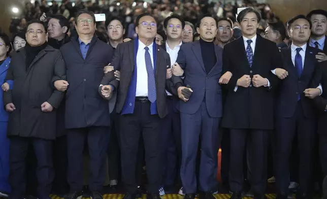 South Korean lawmakers hold arms at the National Assembly in Seoul, South Korea, Friday, Dec. 6, 2024. (AP Photo/Lee Jin-man)
