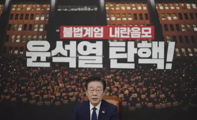 South Korea's main opposition Democratic Party leader Lee Jae-myung speaks during an interview with The Associated Press at the National Assembly in Seoul, South Korea, Friday, Dec. 6, 2024. The part of letters at bottom "Impeachment, Yoon Suk Yeol." (AP Photo/Lee Jin-man)