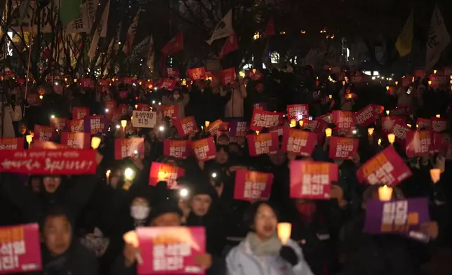 People hold candles during a candlelight vigil against South Korean President Yoon Suk Yeol in Seoul, South Korea, Thursday, Dec. 5, 2024. The letters read "Resign Yoon Suk Yeol." (AP Photo/Lee Jin-man)