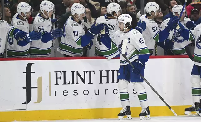 Vancouver Canucks defenseman Quinn Hughes (43) celebrates with the bench after scoring a goal against the Minnesota Wild during the first period of an NHL hockey game Tuesday, Dec. 3, 2024, in St. Paul, Minn. (AP Photo/Craig Lassig)